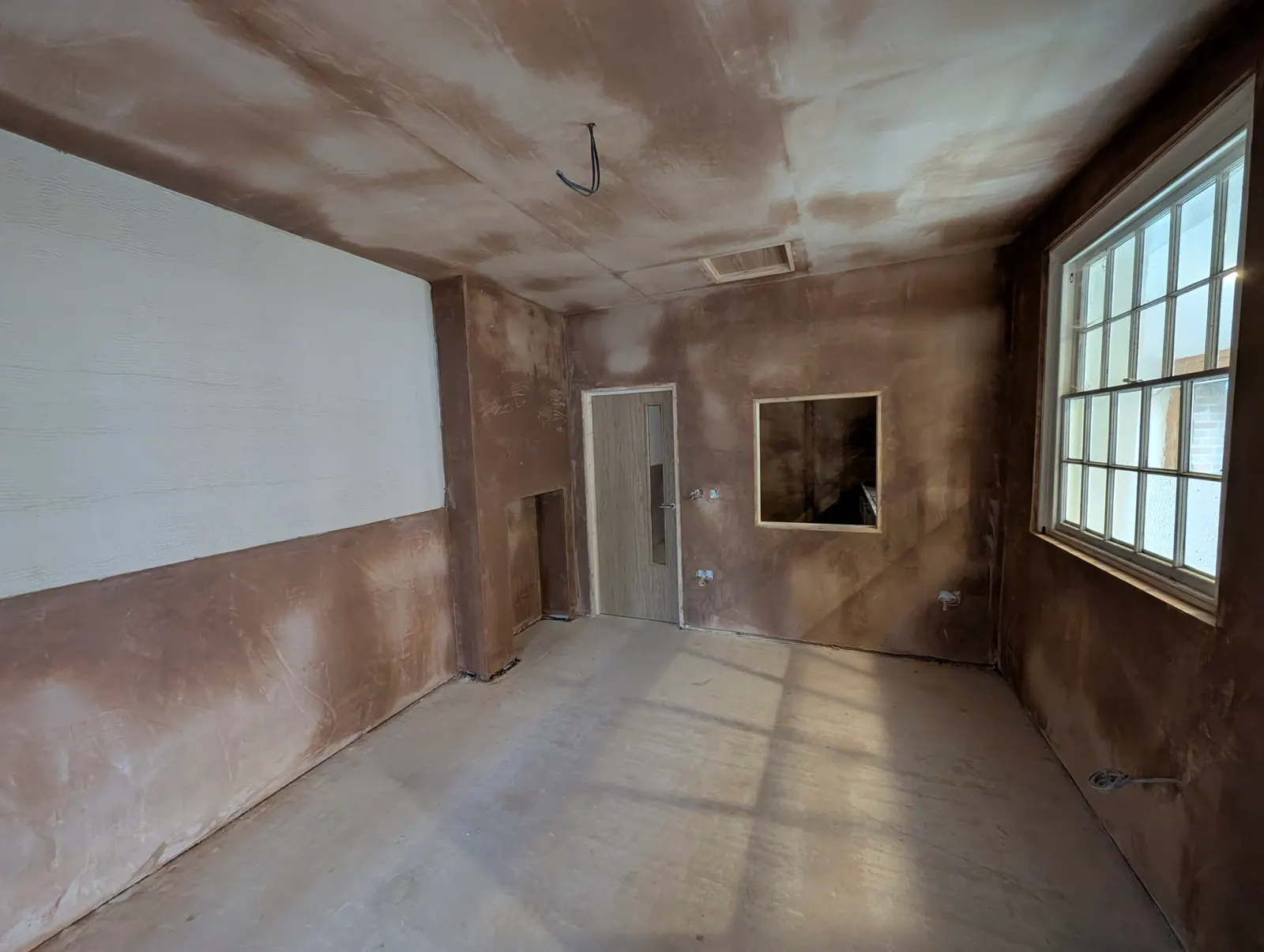 The newly plastered meeting room, with its hatch and door through to the kitchen